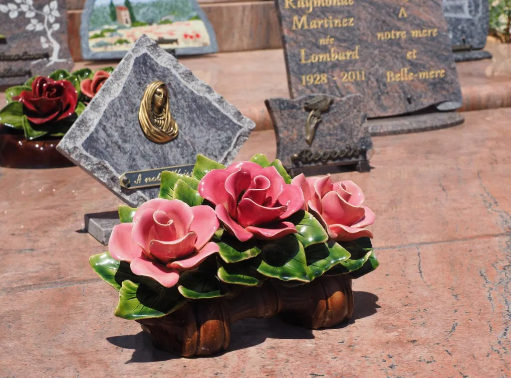 "Fleurs en céramique rose sur une plaque funéraire en granit