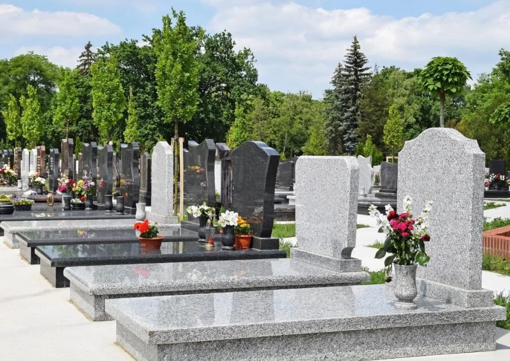 Pierres tombales en granit alignées dans un cimetière paysager